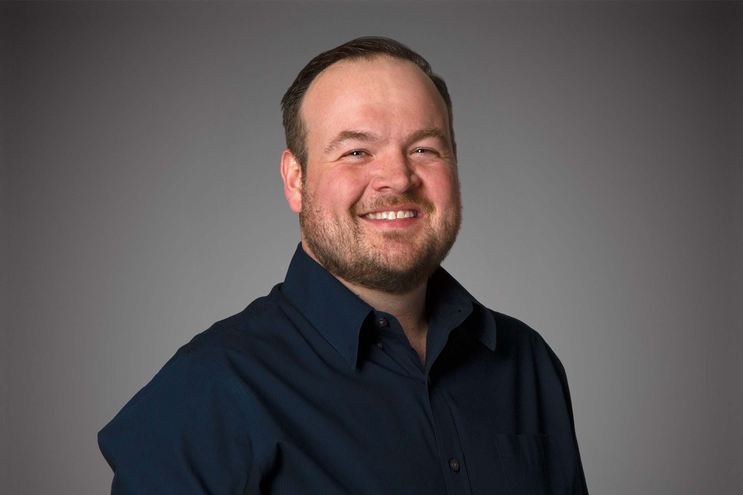Headshot of Colum Hughes in front of a gray background.