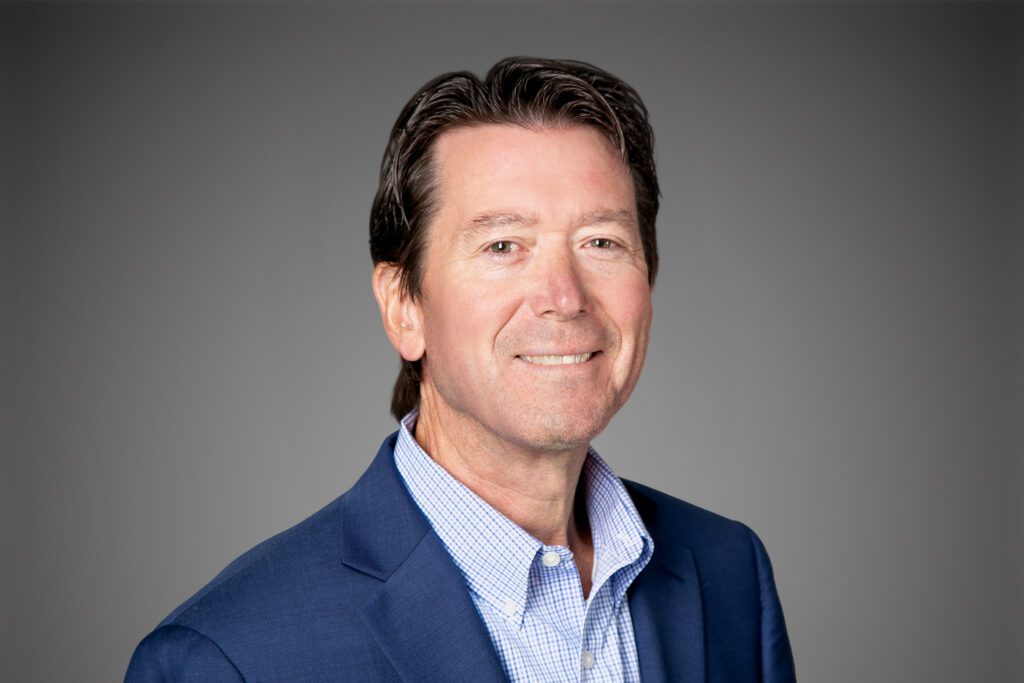 Headshot of Jay Wilson in front of a gray background.