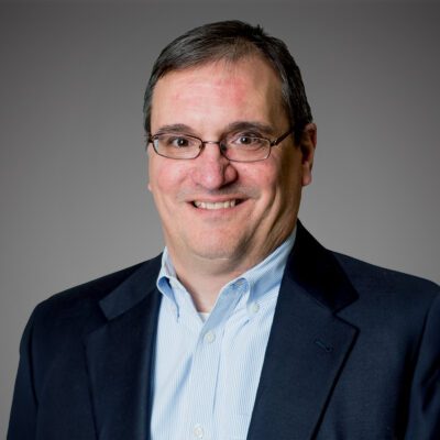 Headshot of Joe Oetter in front of a gray background.