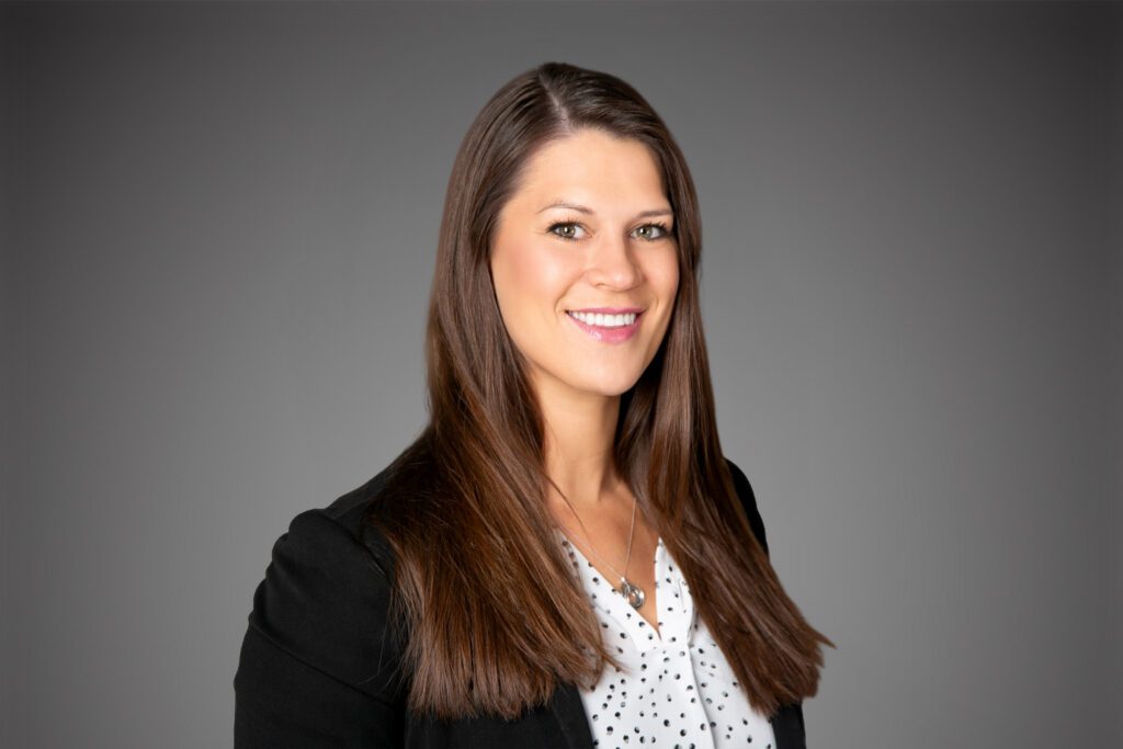 Headshot of Kori Jesenovec in front of a gray background.