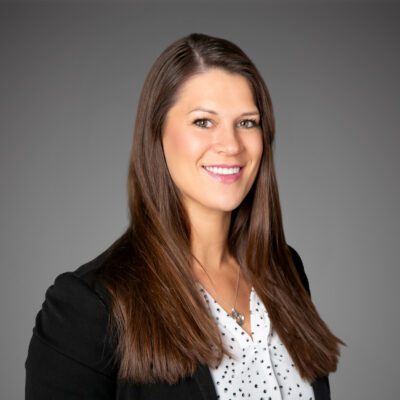 Headshot of Kori Jesenovec in front of a gray background.