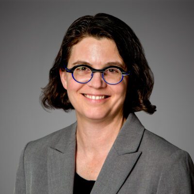 Headshot of Leigh McMillen in front of gray background.