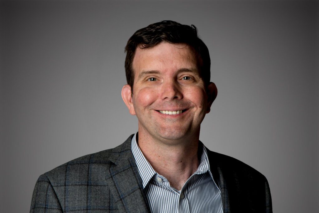Headshot of Michael Mastin in front of a gray background.