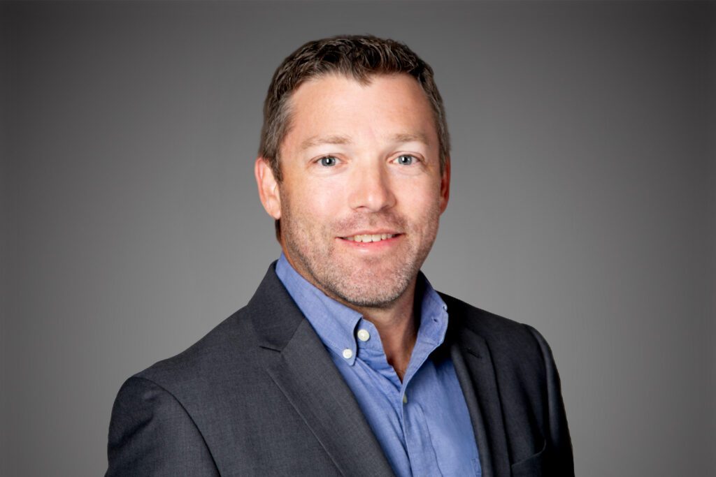 Headshot of Todd Welch in front of a gray background.