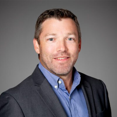 Headshot of Todd Welch in front of a gray background.